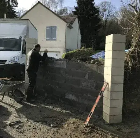 Maçon du Carré Vert montant un mur de clôture en parpaings — Indre-et-Loire (37)