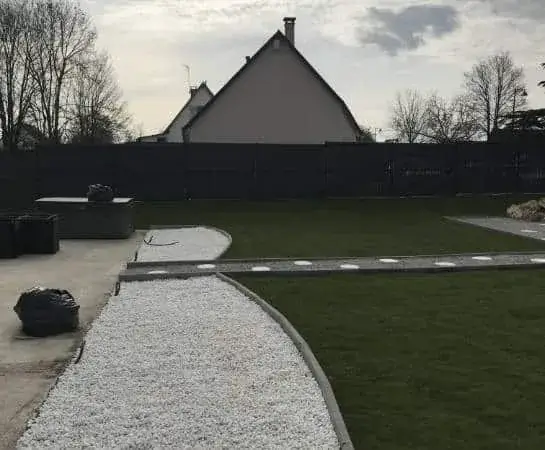 Vue d'ensemble d'un jardin paysager : pelouse, allée de gravier et massifs — Le Carré Vert (37)