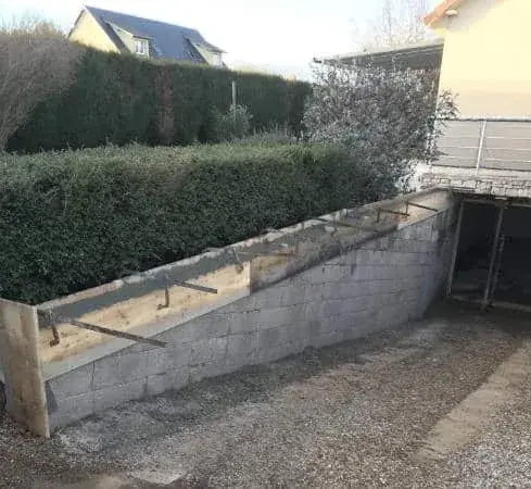Mur de soutènement en parpaings en cours de montage le long d'une rampe de garage — Le Carré Vert (37)